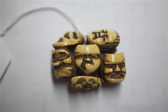 A Japanese ivory netsuke carved with nine Noh masks and another of a seated man asleep, both signed (2)